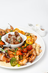 Overhead chicken set platter with roasted wings, corn, veggies and dipping sauces on white