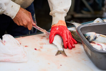 A fish seller in the market cuts fish.