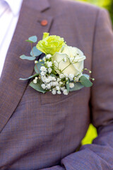 Close-up of groom's boutonniere with a white rose and flowers