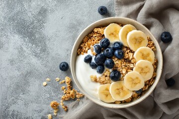 Healthy Breakfast Bowl With Yogurt, Bananas, Blueberries, and Granola on a Wooden Table