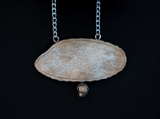 close up of a wooden sign plate hanging on metal chain on black background