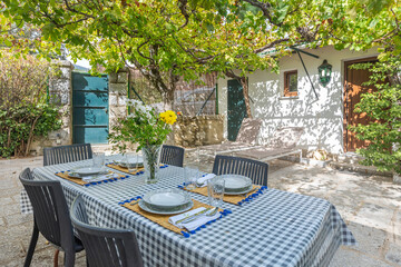  Outdoor dining set with a round table and six rattan chairs under the shade of a wisteria-covered pergola