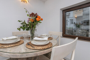 Rustic dining set with a round pitch pine table and slatted chairs, with a bouquet of blue hydrangeas as a centerpiece