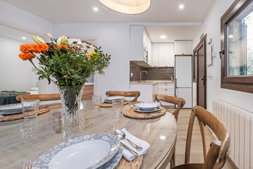 French dining set with a round chestnut table and Louis XV chairs, with a bouquet of lilies and Madonna lilies in a porcelain vase