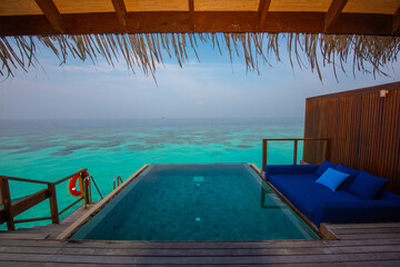 Tranquil closeup calm sea water waves with palm trees. Cabin with pool. Tropical island beach landscape exotic shore coast. Summer vacation, holiday amazing nature. Relax paradise, Maldives.