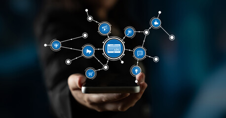 A person holds a smartphone with a visual representation of a digital advertisement network, showcasing various icons symbolizing marketing and online interaction. Tessel