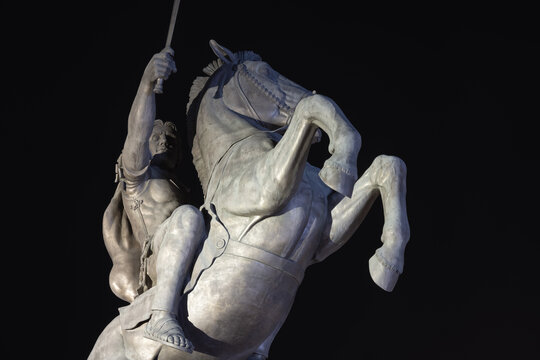 alexander the great bronze equestrian statue against a dark background, depicting the ancient macedonian king and his horse bucephalus.