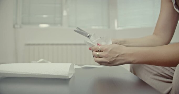 Close-up of a girl's hands meticulously cutting and tearing paper towels with scissors. This video focuses on the clear and crisp sound effects generated, ideal for sound design and relaxing content.