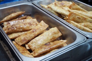 Golden brown, crispy fried pastries in a metal food warmer. Delicious street food or appetizer served at a buffet or catered event