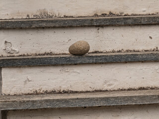 rough stone placed on an aged staircase with peeling paint and visible texture. Perfect for minimalism, balance, resilience, and conceptual or abstract photography