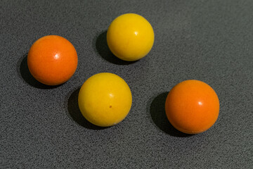 Close-up of four spherical objects in vibrant yellow and orange shades on a gray textured surface. Perfect for minimalist design, geometric concepts, color theory, or abstract composition projects