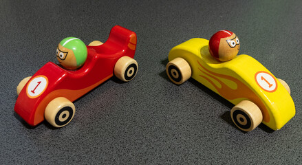 colorful wooden toy race cars, one red and one yellow, on a gray background. Perfect for concepts of childhood, playtime, racing, competition, and creativity