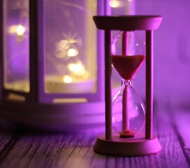 hourglass symbol of passing time and candle light beautiful background