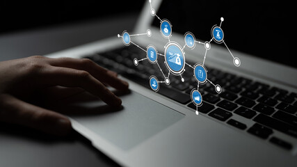 A close-up view of a hand interacting with a modern laptop, featuring digital icons that symbolize...