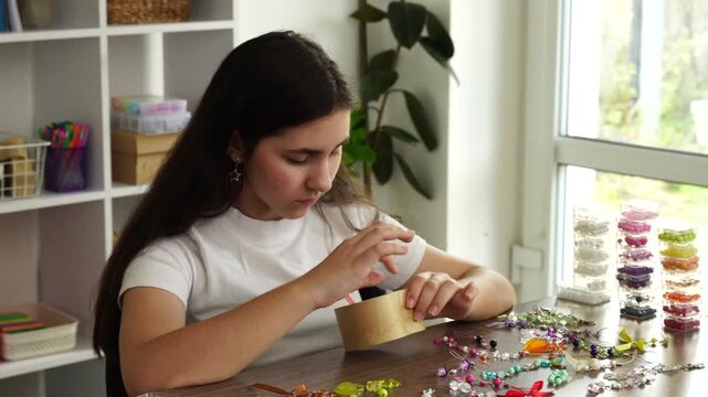 Teenager girl makes keychain from beads, leisure hobby
