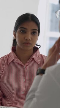 Vertical video compassionate male doctor delivers serious health news and offers support during a worried young woman&rsquo;s hospital consultation