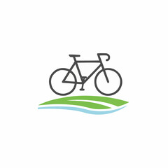 Silhouette of a bicycle on green grass with a blue water stream below it