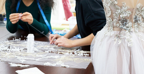 Mannequin with a wedding dress is in the tailor's shop. Dressmaker working in atelier.