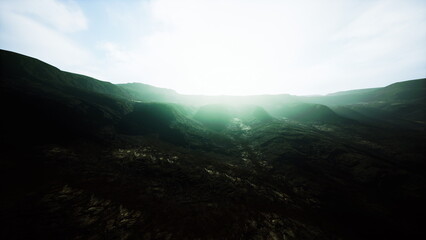 Morning light softly breaks through the valley, revealing rugged mountains and a mysterious mist. The landscape feels serene, inviting exploration and adventure in natures beauty.
