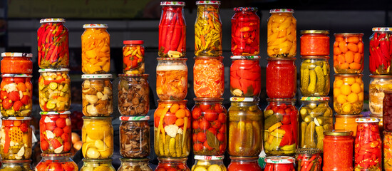 Colorful jars of pickles and peppers on a vibrant market stall display of preserved goods