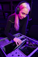 Young woman gamer upgrades a gaming PC, customizing hardware with focus in a high-tech setup