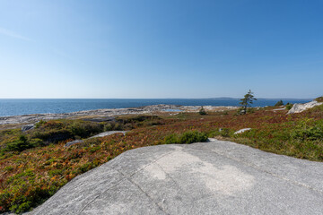Nova Scotia, Canada - October 06, 2025: Driving toward Peggys Cove, a classic Nova Scotia scene appears: a coastal beach with a small house and a fishing boat, glowing under clear autumn skies.