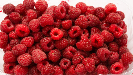 Raspberry in plastic container isolated on white background.
