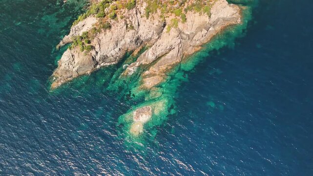Wellen treffen auf einen Felsen im Mittelmeer an der K&uuml;ste der franz&ouml;sischen Insel Korsika. Beruhigend. Vogelperspektive.