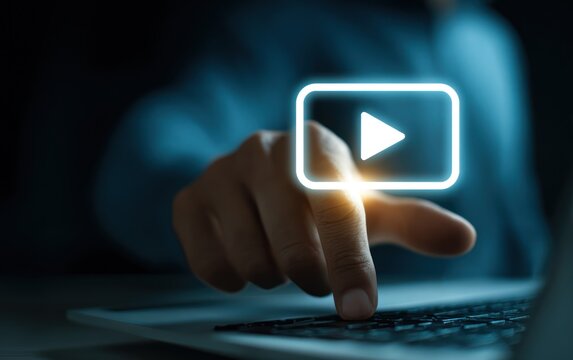 Finger presses glowing play icon above dark laptop keyboard. - Powered by Adobe