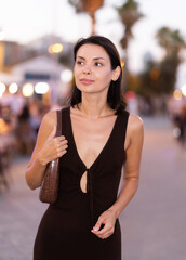 Fototapeta premium Positive young woman in summer dress strolling on busy walkway of Barceloneta beach