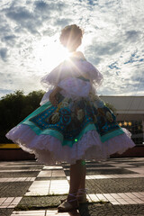 Portrait of an unrecognizable dancer in a traditional dress against a beautiful blue sky in Neiva, Huila, Colombia. Concept of Colombian culture