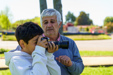 Fototapeta premium Grandfather teaching boy photography in park