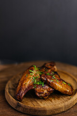 Grilled chicken wings garnished with fresh herbs on wooden plate