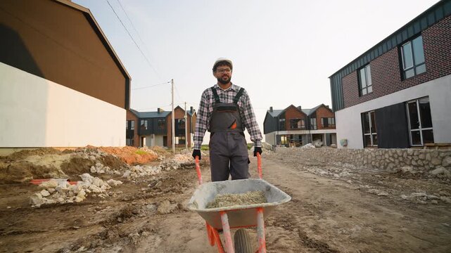 Construction worker pushing wheelbarrow at building site