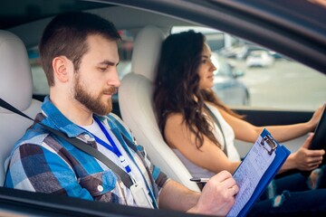 Male instructor completing a report after the driving test. Young woman driving car. Test drive, transportation, safety, education concept