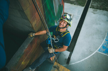 Latino firefighter rescuer rappelling down a building.
