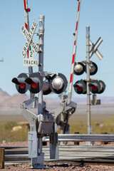 at grade railroad crossing that just along a highway in rural southwest desert of the united state where cargo trains carry goods inexpensively inland from coastal ports