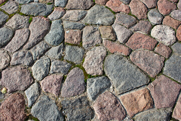 Fragment of a road made of granite stones. Paving stones made of granite stones on an old road. Stone background.