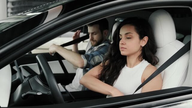 Young lady and male instructor sitting in the car, using seat belts. Slow motion