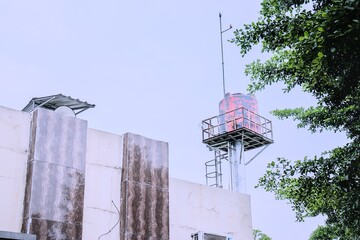 Water tower rises above building with tree branches in the foreground