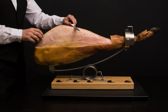 Jam&oacute;n sobre jamonero preparandolo para limpieza y corte con emplatado.