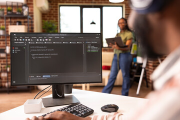 African american software developer typing at home desk, refining code and solving bugs on computer. Male remote worker focuses on improving application performance in home workstation.