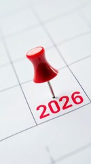 Red pushpin sticking on calendar date 2026 closeup