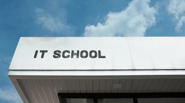 IT School word sign displayed on building facade under clear blue sky, representing information technology training, computer science education, and career development in digital fields.