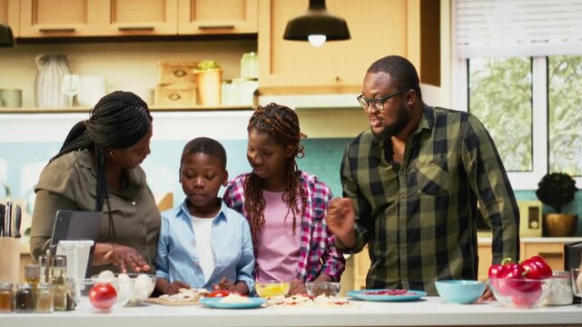 Portrait of parents teaching their kids how to make homemade pizza with fresh ingredients, offering advice and assistance step by step. Family bonding and having fun over culinary hobby. Camera B.