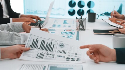 A diverse group of business professionals collaborates in a modern office, analyzing financial data through charts and graphs, fostering teamwork and innovation. SACTR - Powered by Adobe