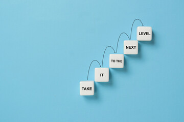 Business career path for growth and success concept. Dice ladder with the message take it to the next level with stepping up arrows
