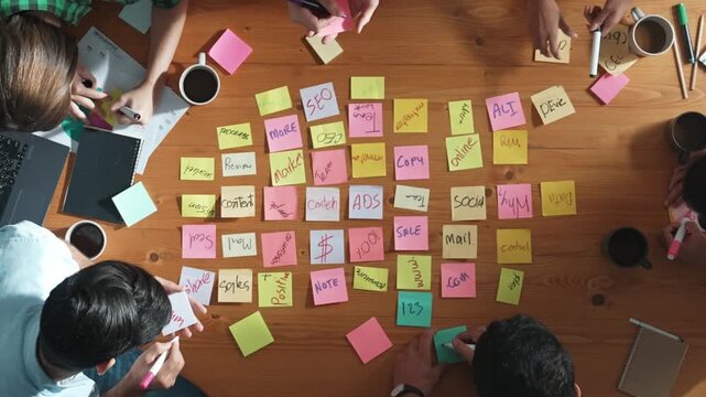 Top down view of smart diverse business people writing marketing idea at meeting and brainstorming start up project strategy or campaign at meeting room. Creative group discussing plan. Convocation.