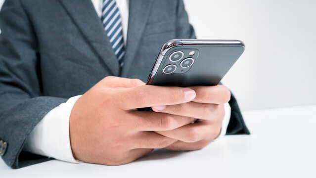 A businessman is using a smartphone to conduct financial transactions via online banking and other transactions via the internet and big data via his smartphone.