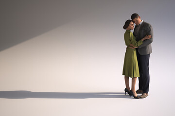 Couple embracing each other tenderly in minimalist attire.